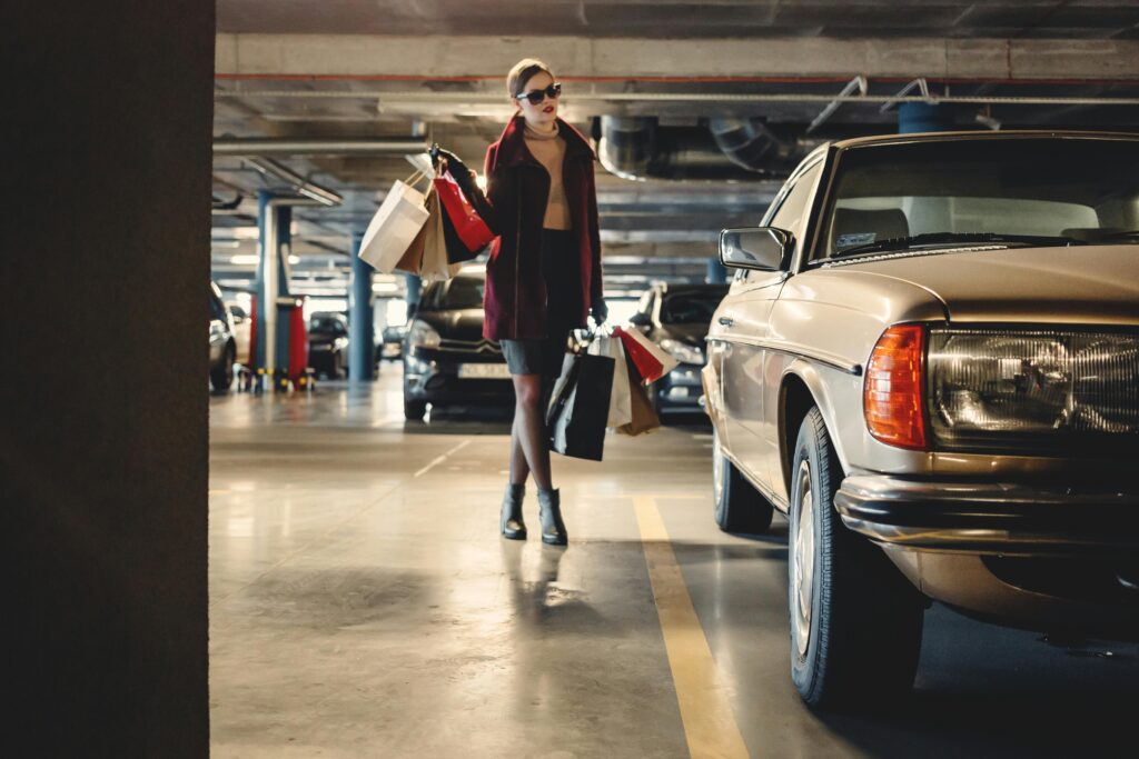A happy traveler carrying shopping bags to her Heraklion rent a car in a city parking lot, enjoying a stress-free day in Crete.